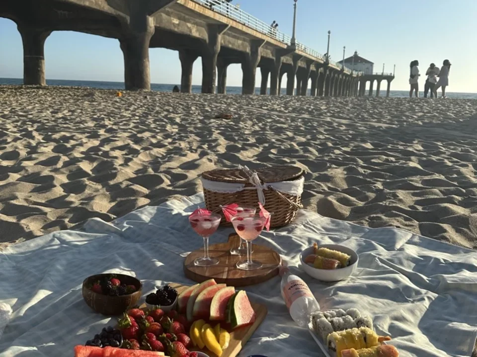 Various fruits and drinks on a picnic blanket. 